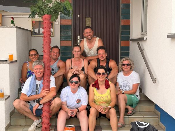 Gruppe von zehn Personen sitzt auf Treppen vor einem Gebäude, fröhliche Stimmung nach dem Abbau.